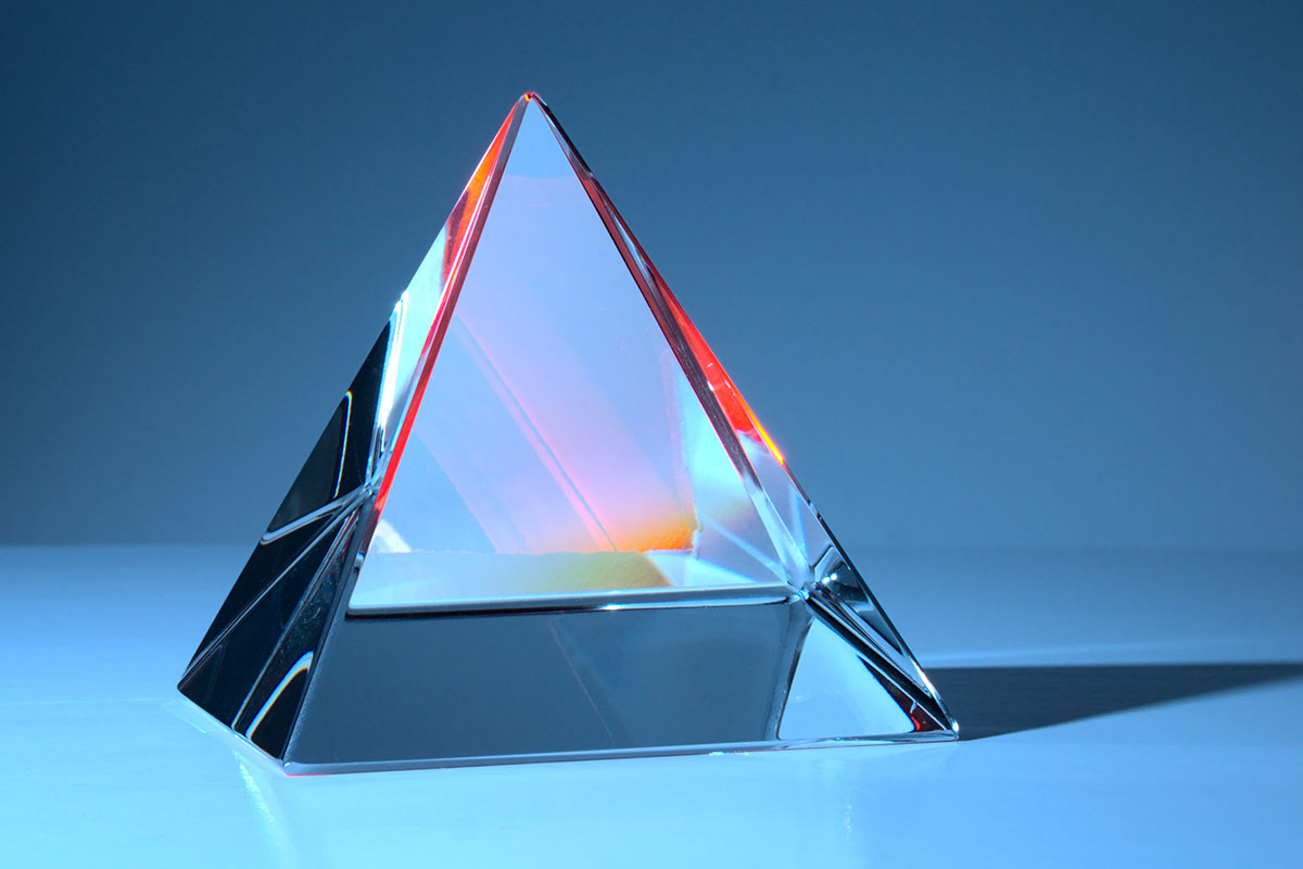 Crystal prism glowing with light on table with neutral background.